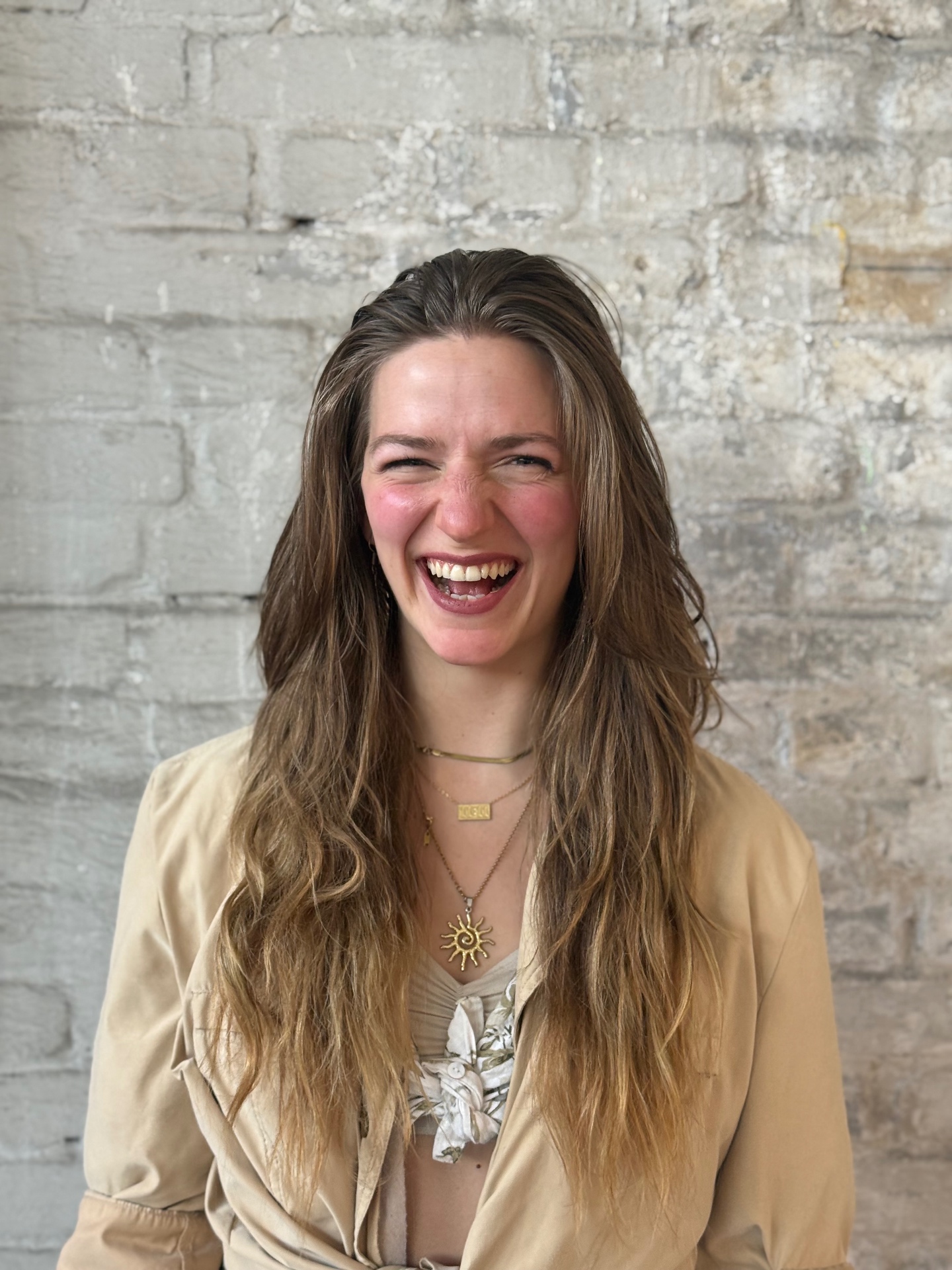 Portrait of Frauke laughing in front of a light brick wall