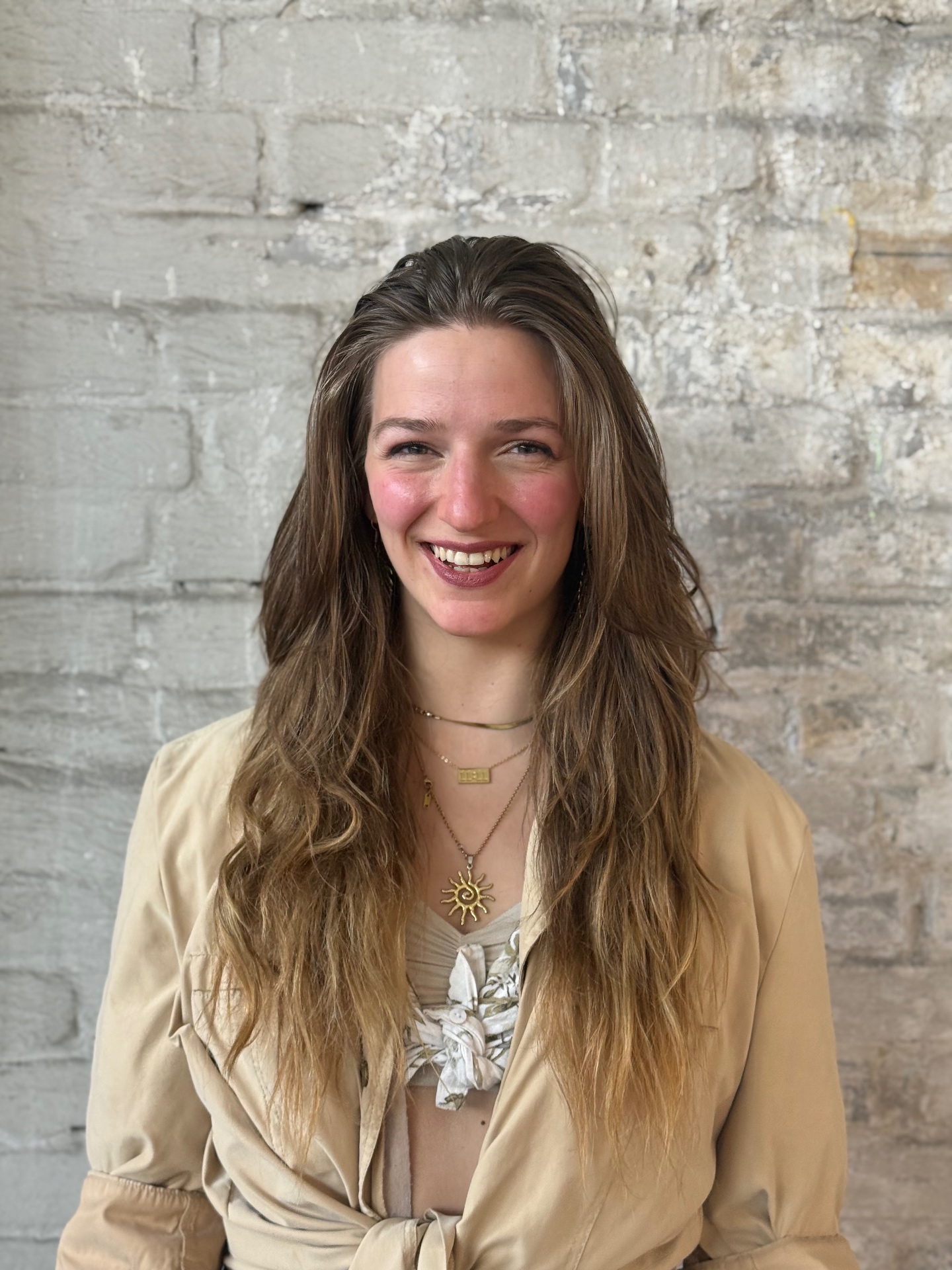 Portrait of Frauke Küble smiling in front of a light brick wall