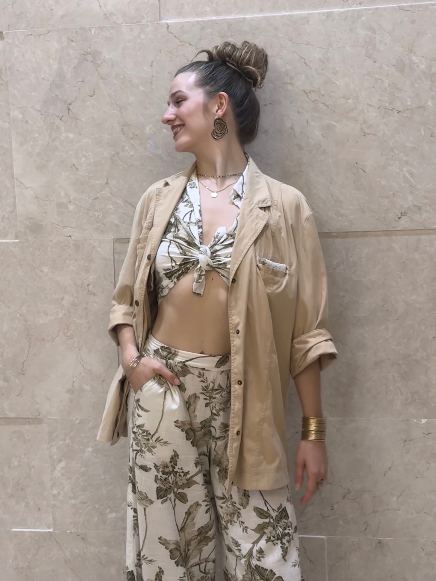 Frauke standing against a marble wall in soft beige tones