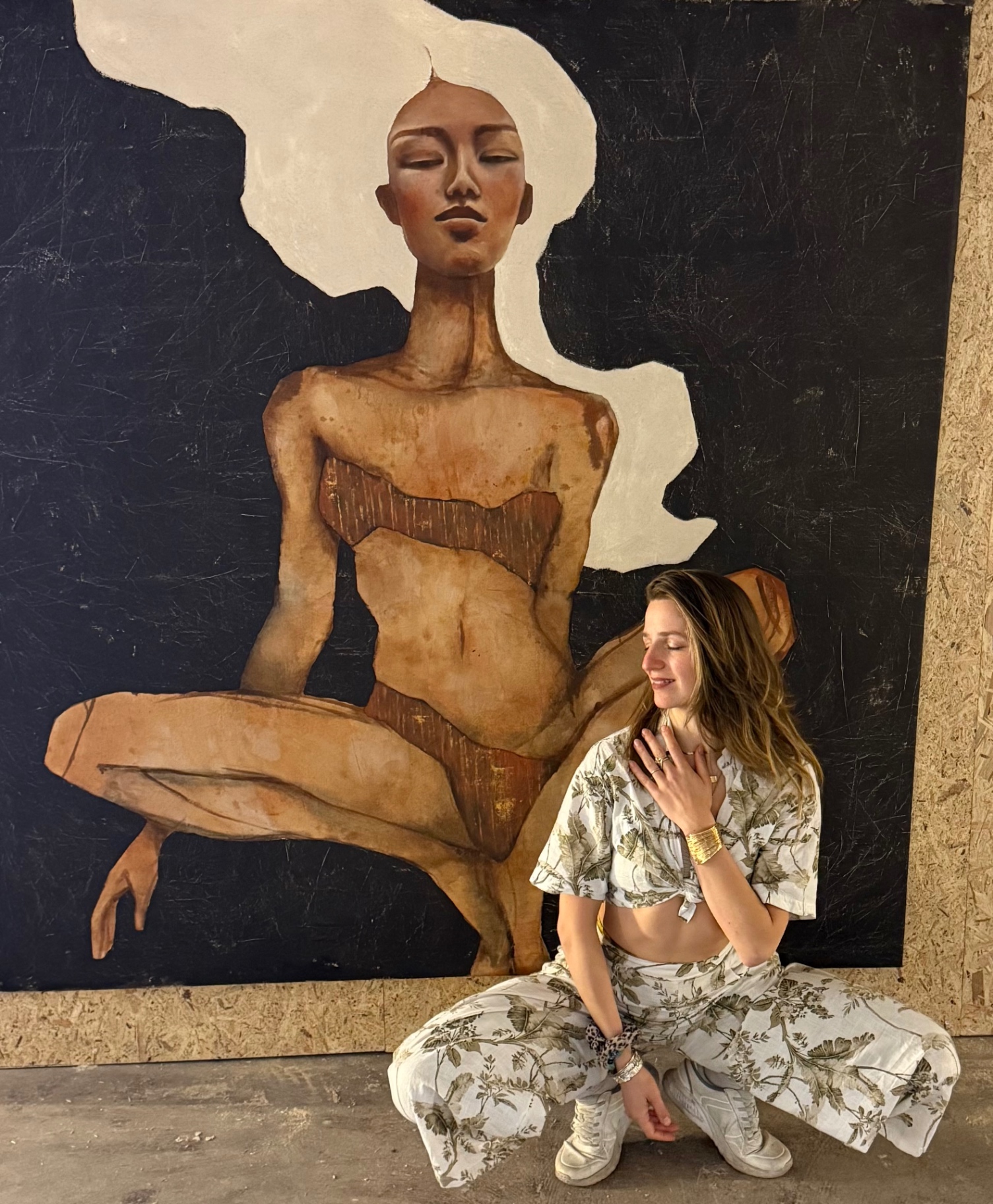 Frauke seated calmly in front of a large painted figure