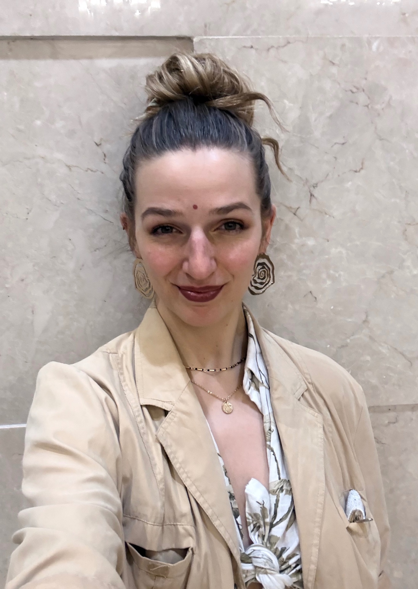 Frauke in a warm beige jacket against a marble wall